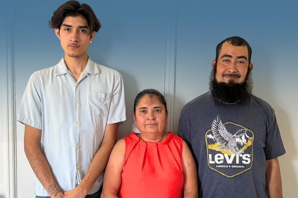 Ms. Eva Oceguera (center) stands in between her two young adult sons.